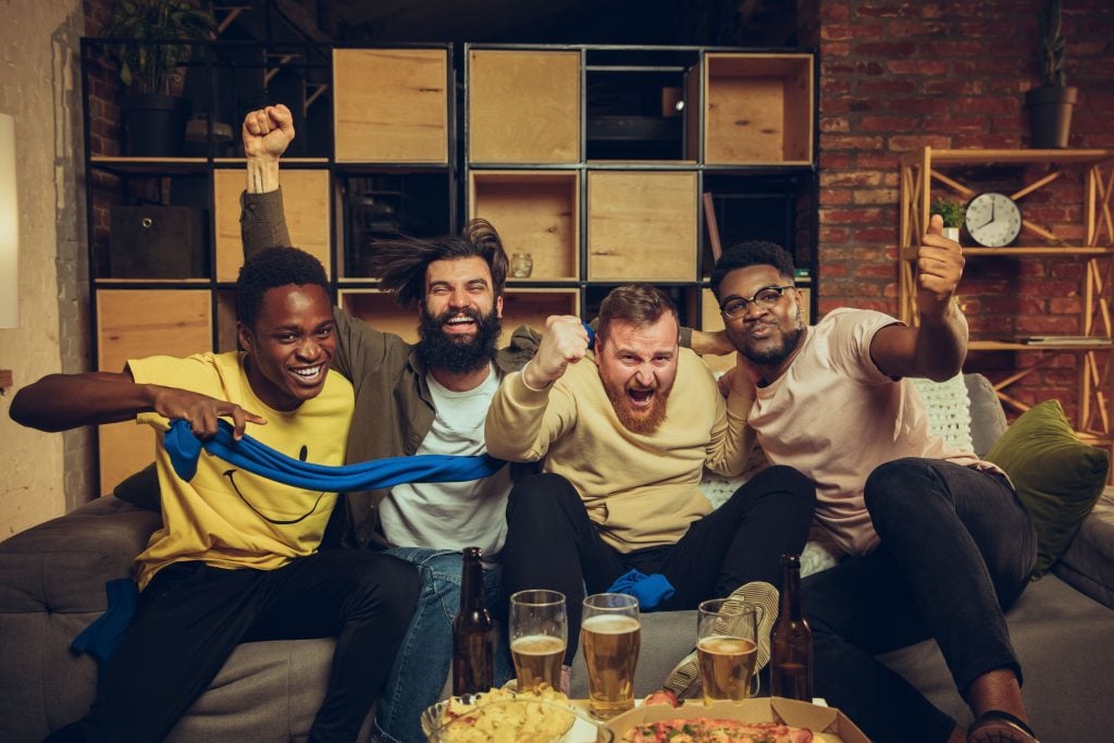 Amigos assistindo a partida de futebol. 