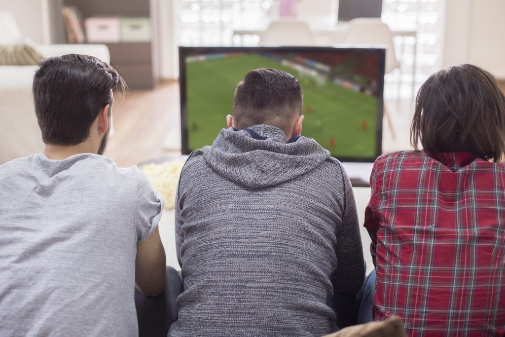 Amigos assistindo a partida de futebol. 