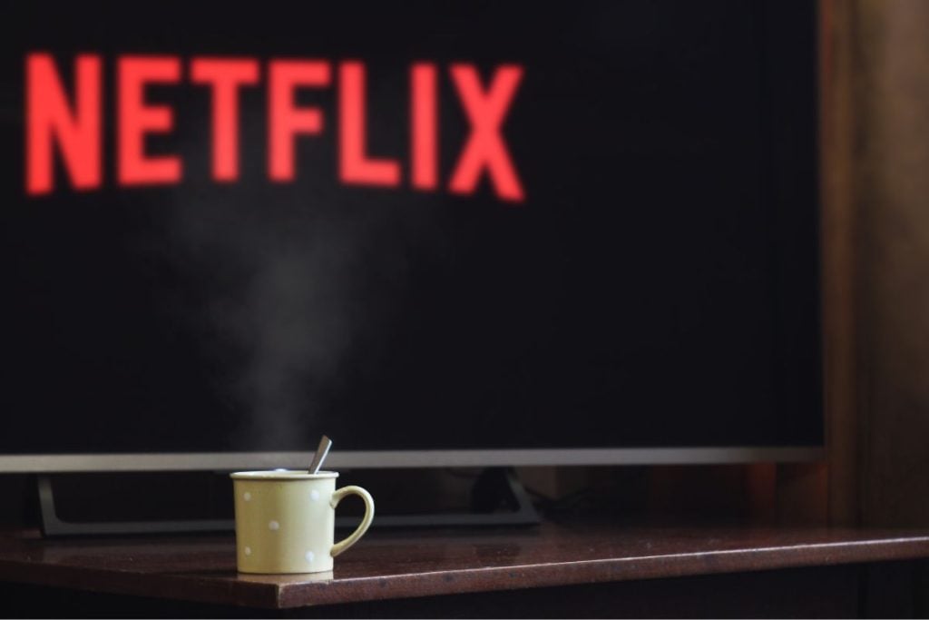 imagem de uma televisão com uma caneca de chá sobre a mesa iniciando para começar a escolher os melhores filmes da netflix