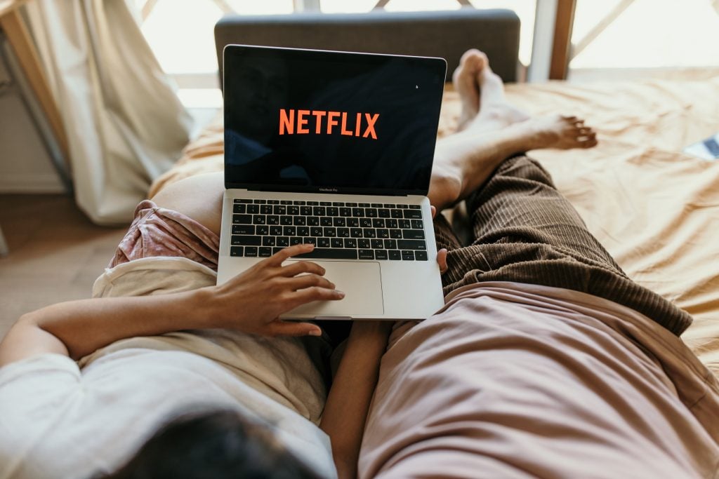 imagem de uma pessoa com notebook no colo após assinar e começar a assistir a netflix