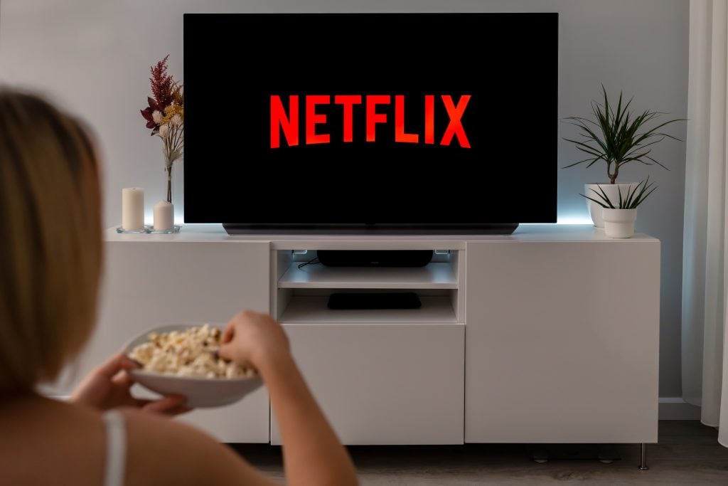 Mulher comendo pipoca enquanto assiste a Netflix.