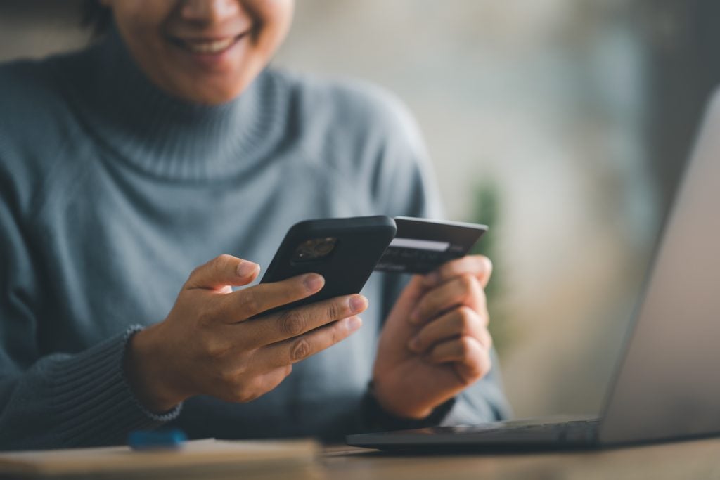 mulher segurando celular e cartão