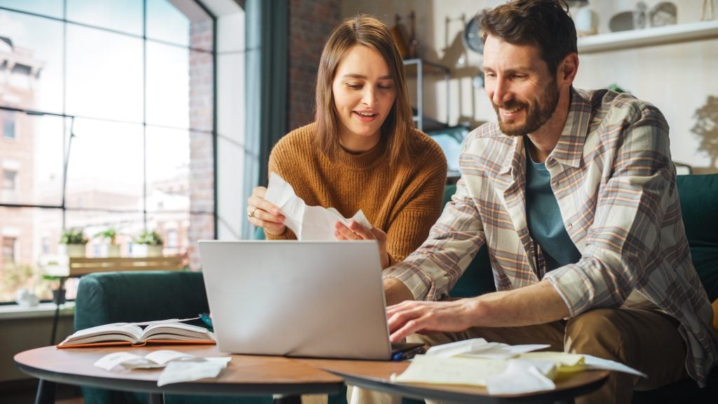 homem e mulher com notebook e contas na mesa